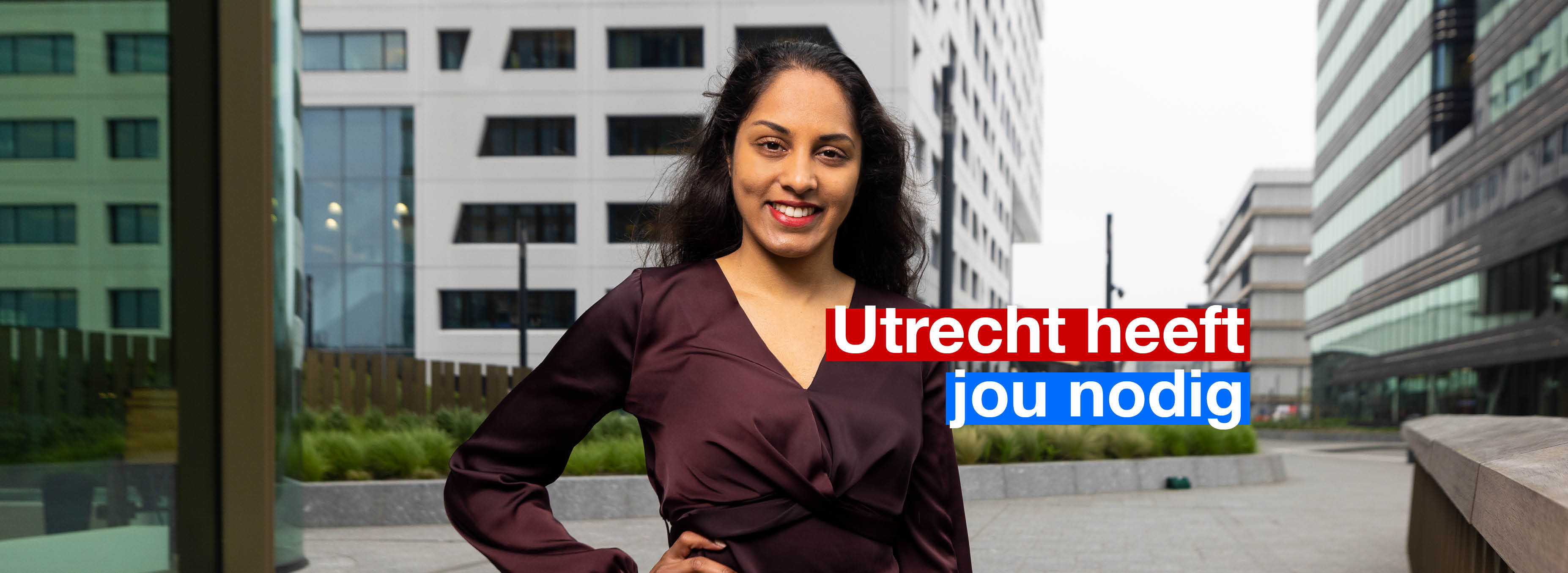 Lachende vrouw met zwart haar. Staat voor het kantoor van Gemeente Utrecht