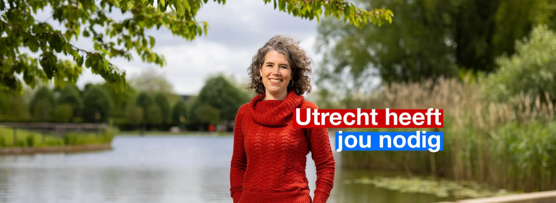 Lachende vrouw met rode trui met op de achtergrond een meer.